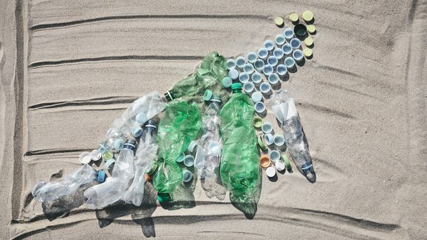 Gráfico feito de garrafas e tampas na areia
. - Foto, Imagem