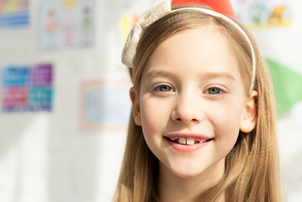selective focus of adorable smiling kid in headband looking at camera - Photo, Image