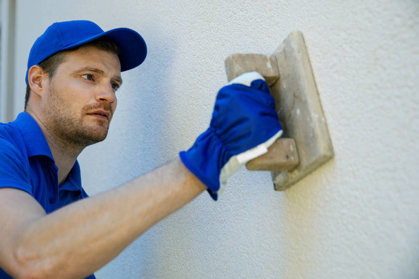 Arbeiter tragen dekorativen Fassadenputz auf Hauswand auf - Foto, Bild