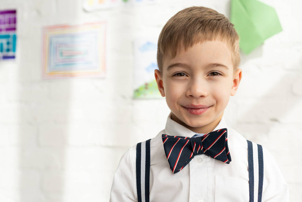 adorable preteen boy in bow tie looking at camera and smiling at home - Photo, Image