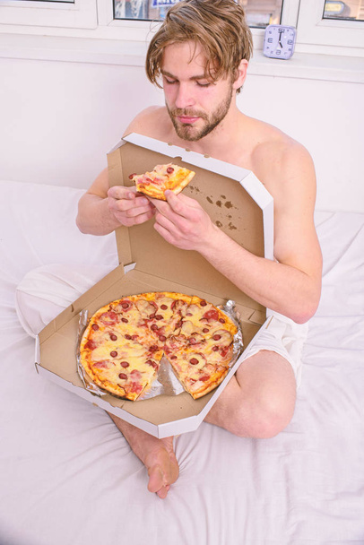 Guy naked covered pizza box sit bed bedroom offer you join him. Sexy courier delivers gastronomic satisfaction. Gastronomic satisfaction. Man bearded handsome eat pizza. Man eat pizza breakfast - Fotografie, Obrázek