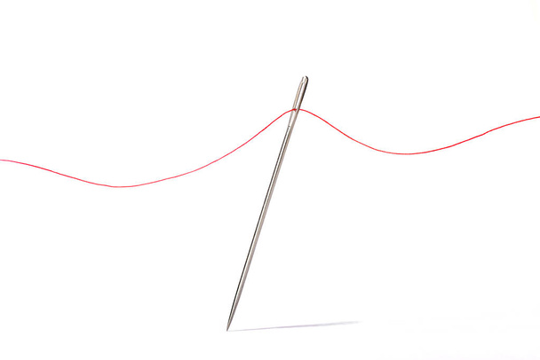 Sewing needle with red thread on black background Stock Photo