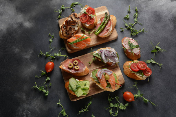 Brushetta or traditional Spanish tapas. Appetizers with Italian antipasti snacks. Variety of small sandwiches with prosciutto, cherry tomatoes, salmon, cream cheese, cucumber, radish, asparagus - Фото, зображення