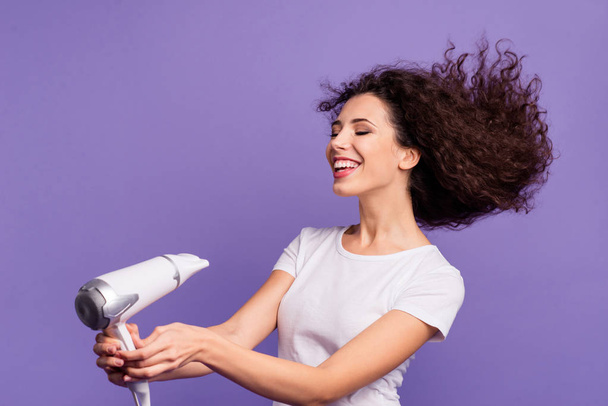 Portrait of nice-looking cute winsome lovely lovable attractive cheerful cheery groomed wavy-haired lady drying strong healthy hair isolated on bright vivid shine violet pastel background - Photo, Image