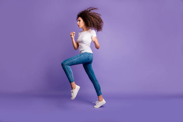 Full length side profile body size photo beautiful amazing she her lady fists jump high shopping rush buy buyer prices wear casual jeans denim white t-shirt sneakers isolated purple violet background - Fotografie, Obrázek