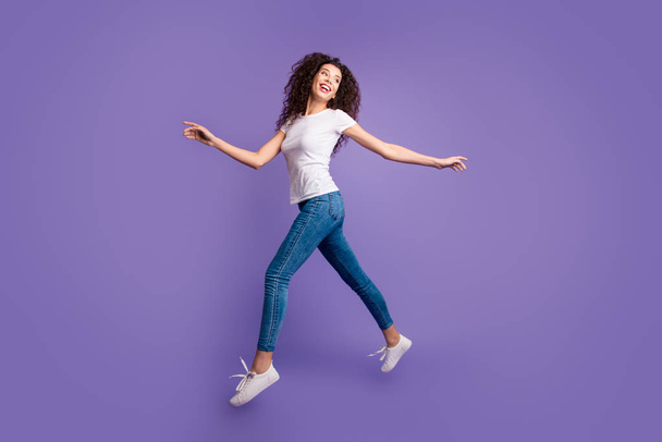 Full length side profile body size photo funky beautiful she her lady jump high spread hands arms shopping store mall wear casual jeans denim white t-shirt sneakers isolated purple violet background - Foto, Imagen