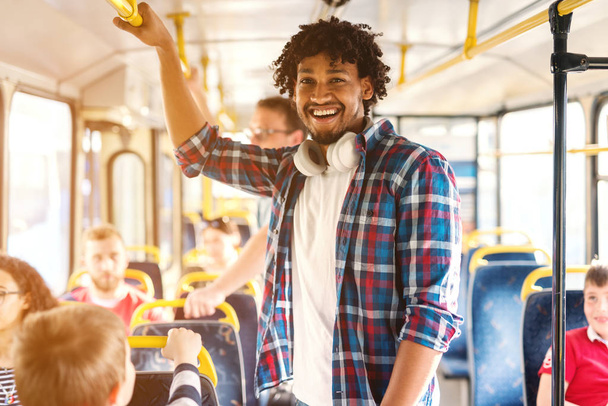 若い笑顔アフリカ系アメリカ人の男が市内バスに乗ってカメラを見て. - 写真・画像