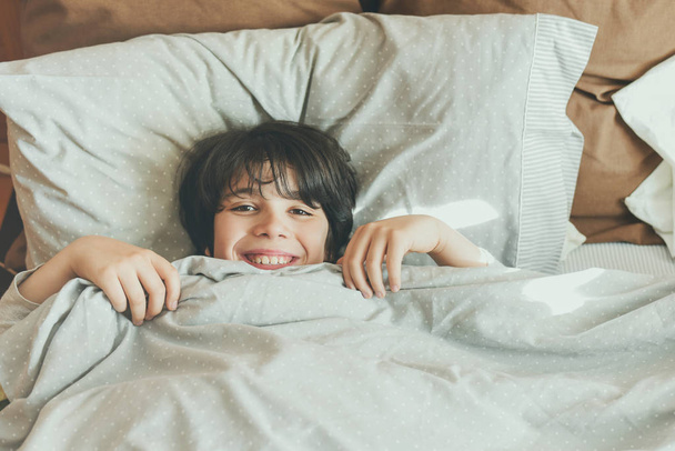 gelukkig kind liggend op het bed  - Foto, afbeelding