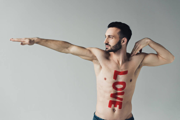Shirtless bearded man with inscription on body posing isolated on grey - Foto, Bild