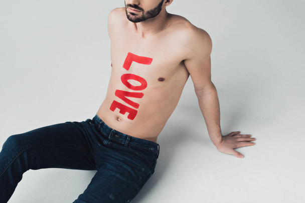 cropped view of shirtless man with inscription on body sitting on grey - Foto, Imagem