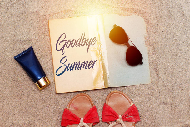 caligrafía adiós verano en libro viejo con tubo de crema azul y gafas de sol negras y sandalia playa sobre arena
 - Foto, imagen