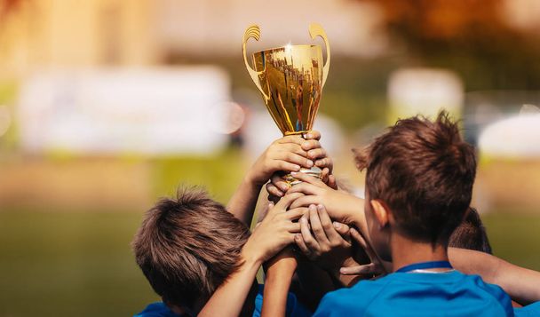 Děti slavící Sport úspěch venku. Hoši, kteří drží zlatý pohár  - Fotografie, Obrázek