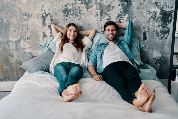beautiful young couple in love lying in bed at home and looking at camera  - Foto, imagen