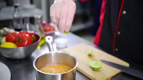 ein Koch in der Küche. Limettensaft in die Suppe geben - Filmmaterial, Video