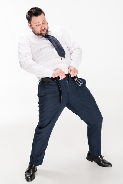 hombre con sobrepeso en ropa formal ponerse pantalones ajustados en blanco
 - Foto, Imagen