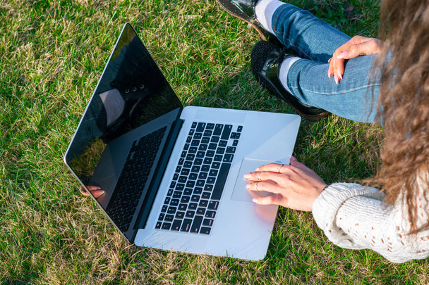 cropped shot of woman using laptop on green grass - Foto, imagen