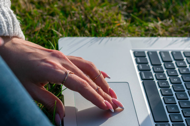 обрізаний знімок жінки, використовуючи ноутбук на зеленій траві
 - Фото, зображення
