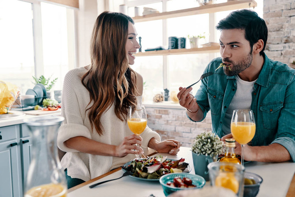 beautiful young couple enjoying healthy breakfast while sitting in the kitchen at home - Fotoğraf, Görsel