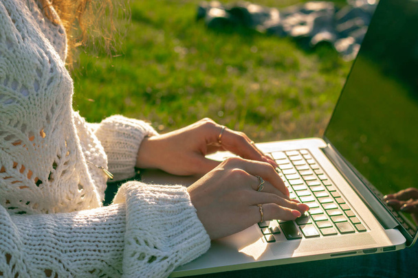plan recadré de la femme en utilisant un ordinateur portable sur l'herbe verte
 - Photo, image
