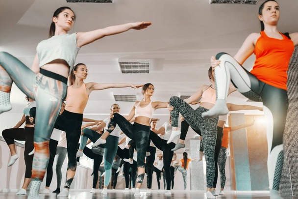Group of focused Caucasian women dressed in sportswear standing on one leg and balancing. Never let your laziness decide your future. - Photo, Image