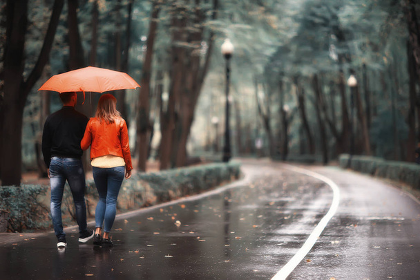 rain in the autumn park / young 25 years old couple man and woman walk under an umbrella in wet rainy weather, walk October lovers - Zdjęcie, obraz