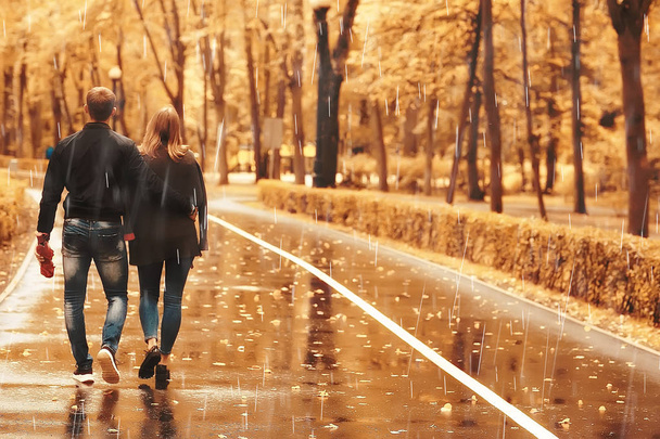 rain in the autumn park / young 25 years old couple man and woman walk under an umbrella in wet rainy weather, walk October lovers - Foto, imagen
