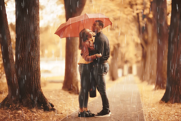 rain in the autumn park / young 25 years old couple man and woman walk under an umbrella in wet rainy weather, walk October lovers - Фото, зображення
