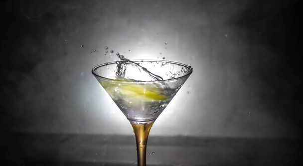 Martini cocktail lasi roiskeita tumma sävyinen savuinen tausta tai värikäs cocktail lasi roiskeet ja sitruuna. Juhlakerhon viihdettä. Sekavalo. Valikoiva painopiste
 - Valokuva, kuva