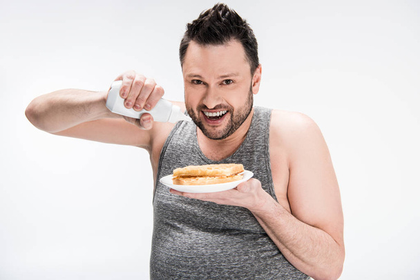 happy overweight man holding bottle of syrup and waffles isolated on white - Foto, immagini