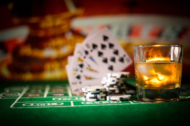 szerencsejáték, szerencse, játék- és szórakoztató koncepció - közelről kaszinó zseton és whiskys pohár asztalnál. Szelektív összpontosít - Fotó, kép