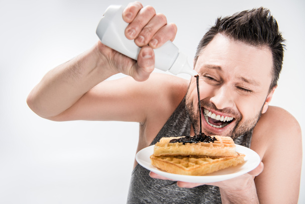 mutlu tombul adam beyaz waffle üzerine çikolata şurubu dökülüyor - Fotoğraf, Görsel