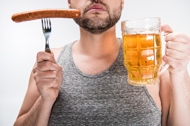 vista recortada del hombre regordete sosteniendo salchicha y vaso de cerveza aislado en blanco
 - Foto, imagen