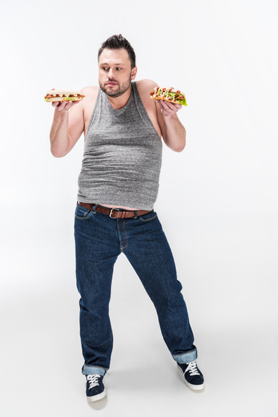 overweight man in tank top holding hot dogs on white - Valokuva, kuva