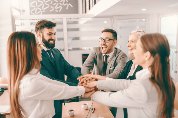 Group of cheerful corporate businesspeople in formal wear stacking hands at meeting in boardroom. Catch your people doing something right and let them know you appreciate it. - 写真・画像