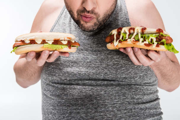 részleges kilátás a túlsúlyos férfi gazdaság finom hot dog izolált fehér - Fotó, kép