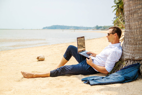 τηλεργασία, επιχειρηματίας χαλαρώνοντας στην παραλία με φορητό υπολογιστή και φοίνικες, ελεύθερος επαγγελματίας στον χώρο εργασίας, εργασία όνειρο - Φωτογραφία, εικόνα