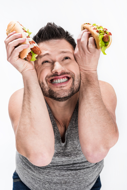 šťastný muž s nadváhou, který drží Hot Dog izolovaný na bílém - Fotografie, Obrázek