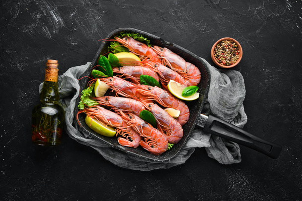 Large grilled shrimp in a frying pan. Tiger prawns. Top view. Free space for your text. On the old background. - 写真・画像