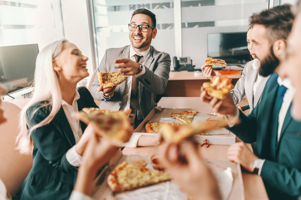 Kis csoport boldog kollégák formális viselet beszélgetni és étkezési pizza együtt ebédelni. Talent győzelem játékok, Tut csapatmunka győzelem bajnokság. - Fotó, kép