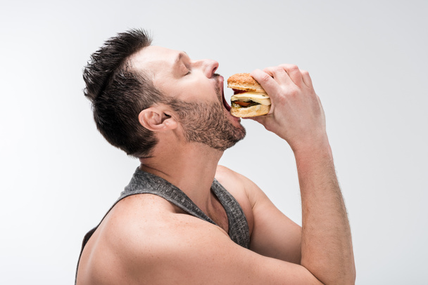 vue latérale de chubby barbu homme manger délicieux hamburger isolé sur blanc
 - Photo, image
