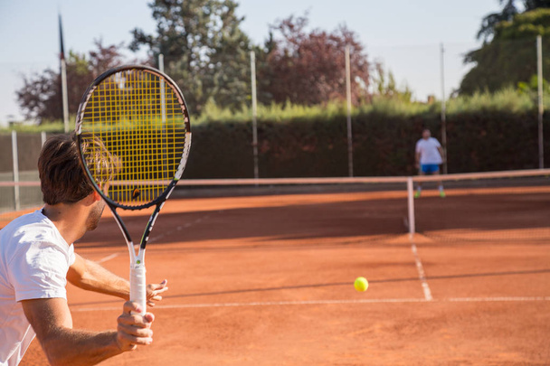 Jugador de tenis profesional hombre jugando en la cancha por la tarde
. - Foto, Imagen