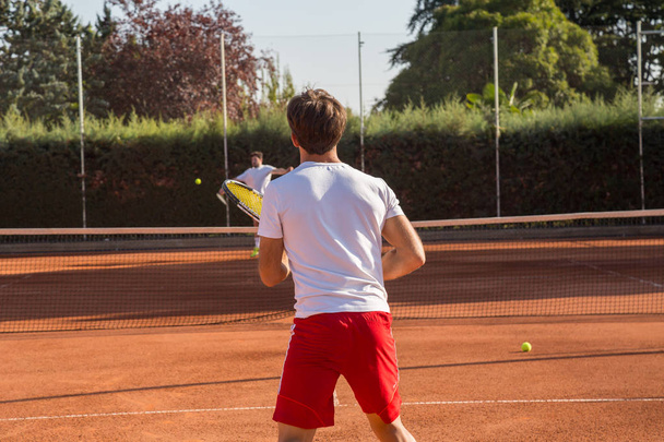 Επαγγελματικού τένις άνθρωπος παίκτης παίζει στο γήπεδο το απόγευμα. - Φωτογραφία, εικόνα