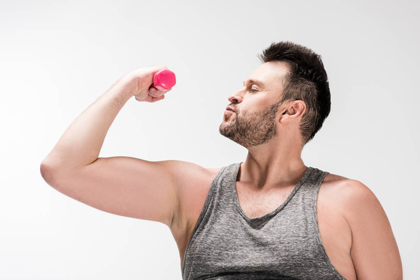 overweight bearded man in tank top working out with pink dumbbell isolated on white - Photo, Image