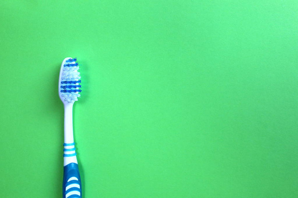 One toothbrush lies on a green background - Zdjęcie, obraz