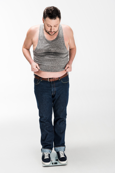 白で隔離された電子体重スケールに立っている太りすぎの男性 - 写真・画像