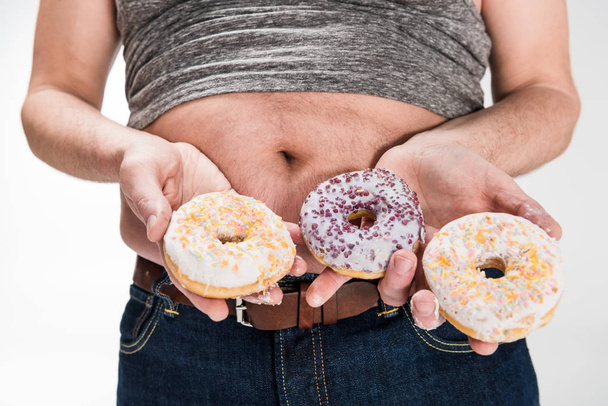 abgeschnittene Ansicht von übergewichtigen Mann mit Donuts isoliert auf weiß - Foto, Bild