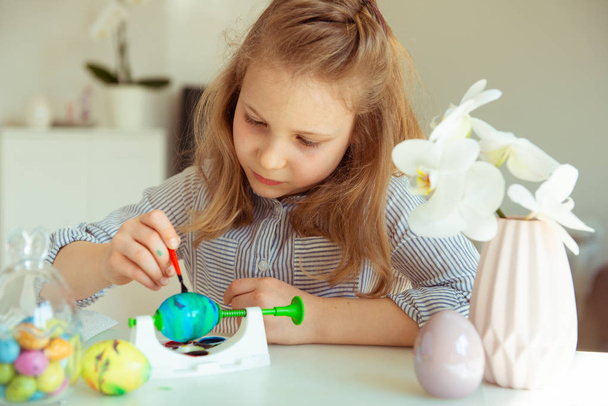 Cute little blonde girl painting Easter eggs - Foto, afbeelding