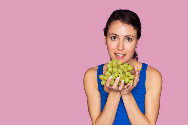Portrait of young woman with fresh grapes isolated on pink background - Foto, immagini