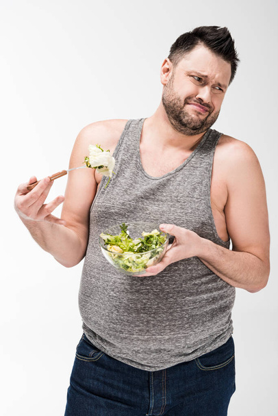 ontevreden overgewicht man Holding Bowl van salade geïsoleerd op wit - Foto, afbeelding
