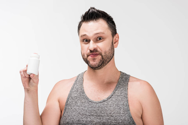 Человек с избыточным весом держит бутылку с лекарствами и смотрит на камеру, изолированную на белом
 - Фото, изображение